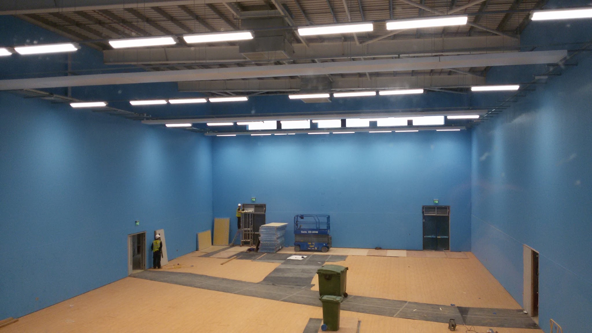 A large blue-walled room with rows of new ceiling lights